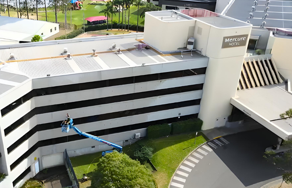 Mercure Hotel Penrith window cleaning — Shimmer technician on boom lift cleaning external glass façade